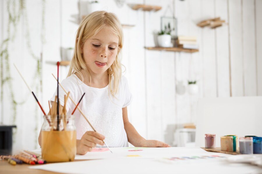 shot-adorable-blonde-girl-with-freckles-biting-her-tongue-because-inspiration-while-painting-girl-with-blond-hair-sitting-room-filled-with-morning-light-wearing-white-clothes_176420-15614.jpg